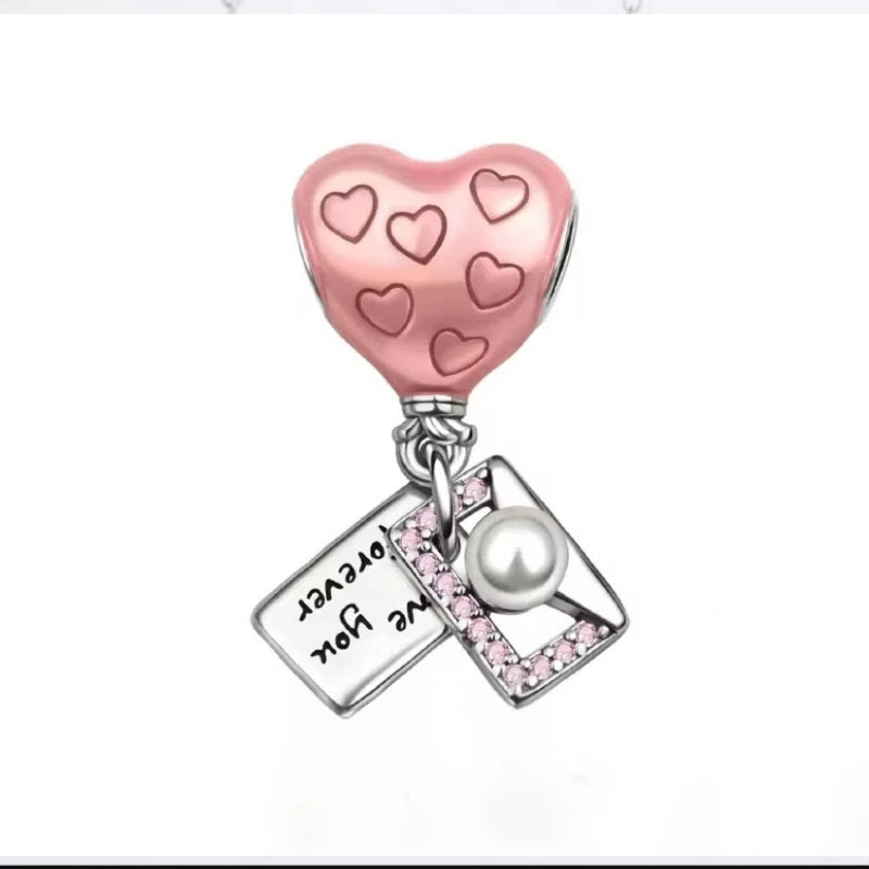 Heart-shaped charm with pink hearts and a pearl on a white background