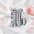 Silver charm with '16' and sparkling stones on a soft pink floral background