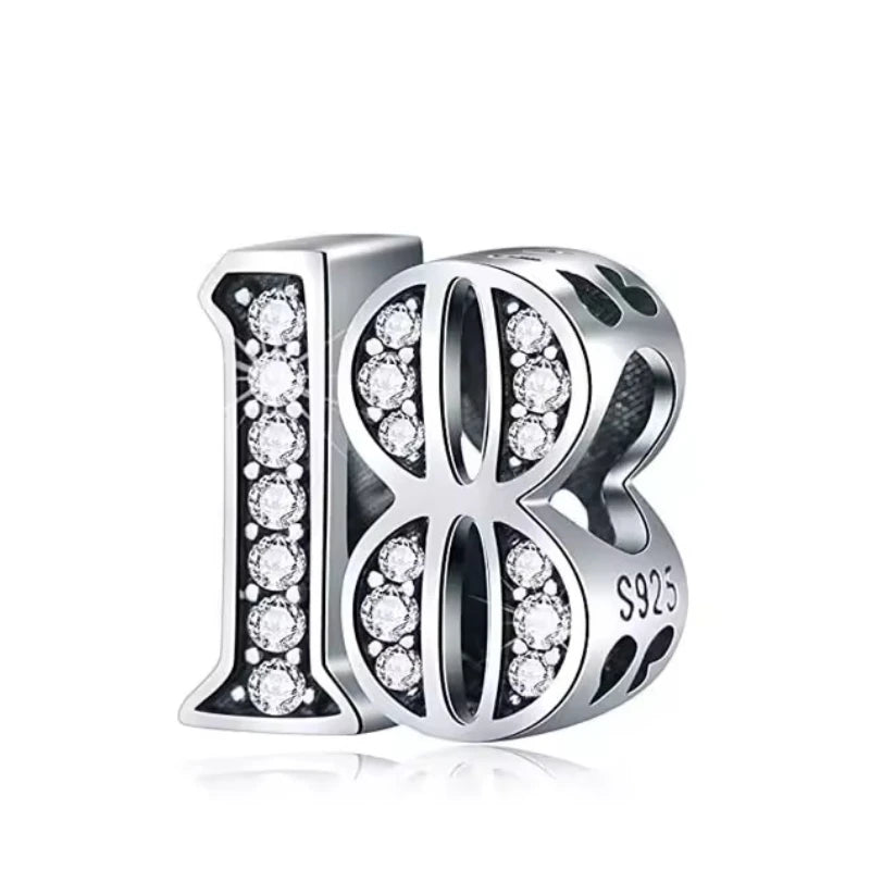 Silver number 18 charm with embedded stones on a white background