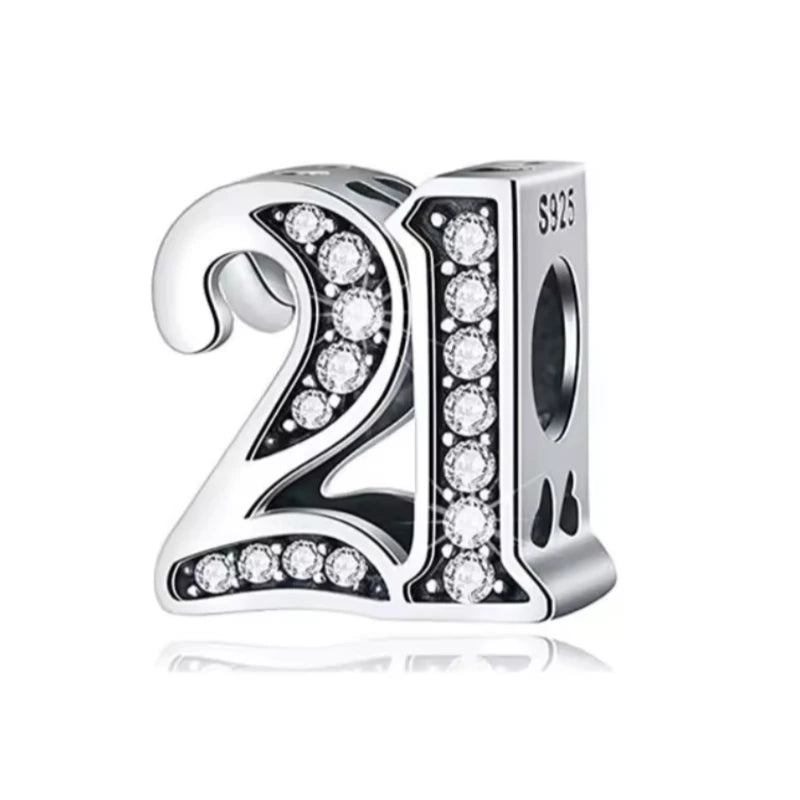Silver charm with '21' and clear stones on a white background