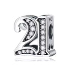 Silver charm with '21' and clear stones on a white background
