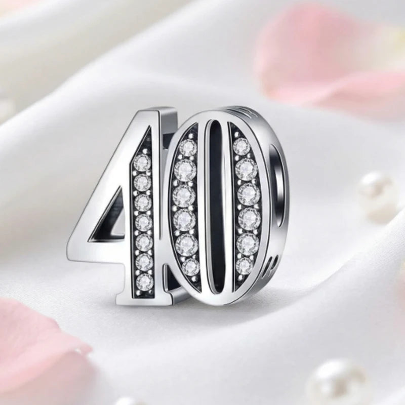 Silver charm with '40' and clear stones on a soft pink background