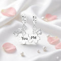 Silver puzzle piece earrings with 'You' and 'Me' text on a soft white background